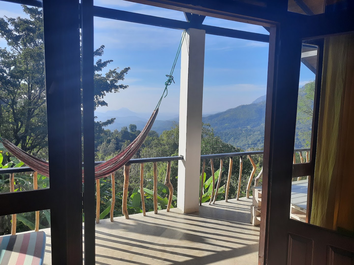 Open timber doorway looking across a hammock and green mountain valley