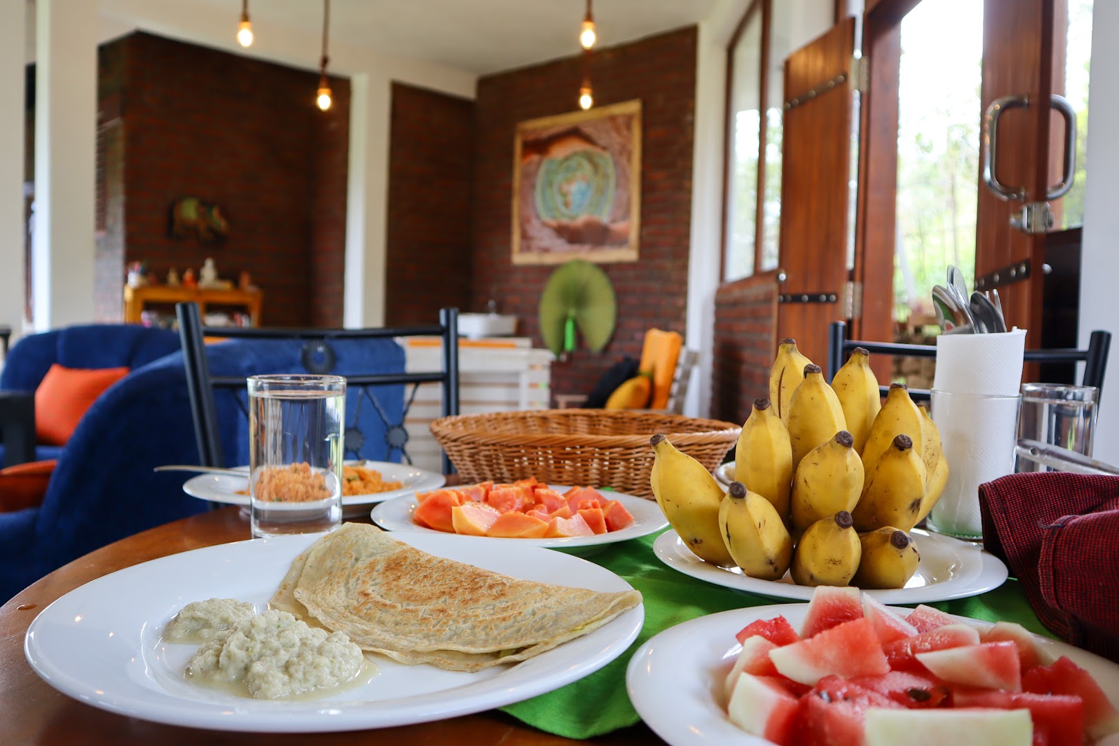 Breakfast table with hoppers, fruit, bananas, and water