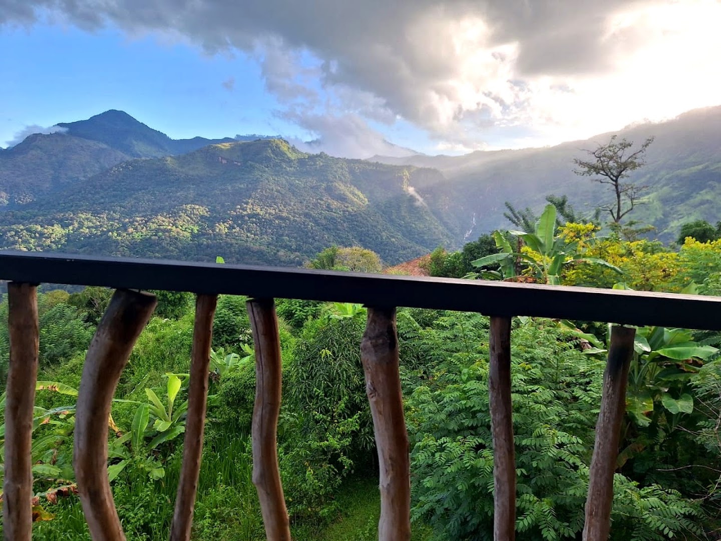 Mountain valley and waterfall beyond a natural timber balcony railing